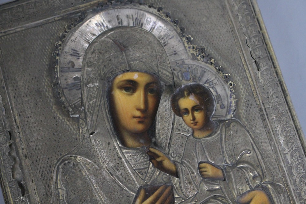 A Russian white metal overlaid tempera on panel icon, depicting the Virgin Mary and Christ child, 22 x 17.5cm